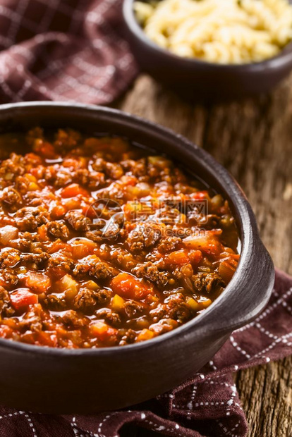 乡村炖重点用豆肉新鲜西红柿洋葱和大蒜制成的自素食肉汤酱以生锈碗为服务在后选择焦点中煮意大利面将三分之一的热点放在酱汁VeganS图片