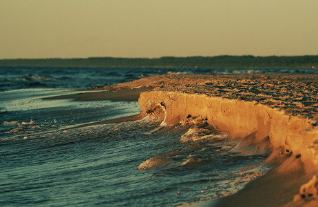 风景波浪海岸与沙一起玩海浪被温暖的夏日夜晚阳光笼罩图片