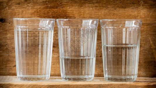 新鲜的清爽喝三杯水用自然光照亮放在木板上的三杯水图片