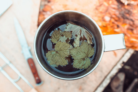 木板给旅行者的茶金属杯子和木制桌上的刀自然甑图片