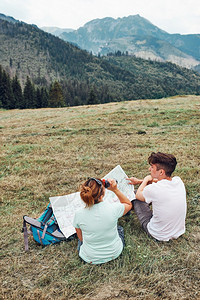 白种人一家在山区度假旅行期间坐在草地上查看山区试验人们在山上度假期间积极地在户外度过时间女士部图片