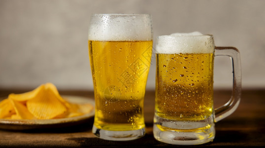 玻璃丈夫两杯啤酒和一盘马铃薯片放在桌边情侣或两个朋友饮用水概念上酒吧图片