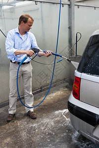 肥皂水男人用高压喷水雾自己洗车的时候把推下来软管中间灯背景