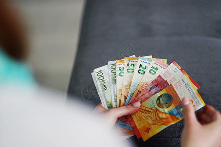 投资国际的持有欧元和瑞士法郎现钞手持家庭清点金融信贷支付现的家庭预算财政妇女士图片