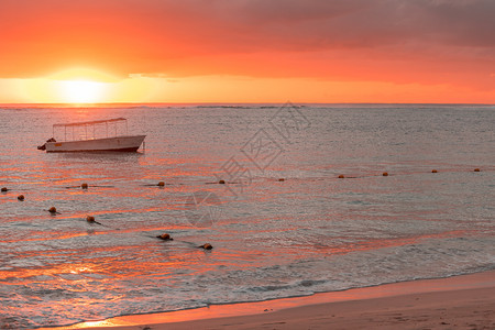 海洋在橙色日落Mauritius海滩Flic和Flac停靠在海滩岸附近的渔船毛里求斯海景图片