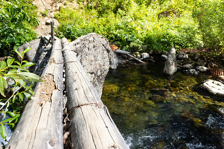 水由山河对面的林木和绳子组成的旧木制旅游桥绿色建造图片