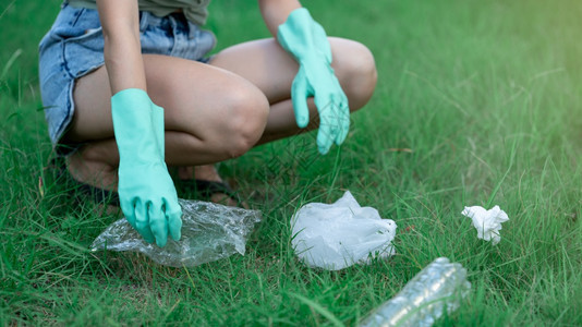 肮脏的绿色帮助妇女手把塑料废物放在公园的黑袋中脏废物在她的手中图片