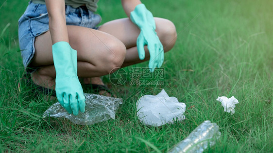 肮脏的绿色帮助妇女手把塑料废物放在公园的黑袋中脏废物在她的手中图片