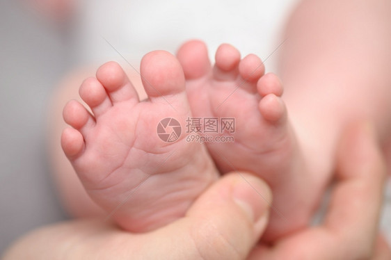 母亲双手握着新生儿小脚大型闭合选择焦点大型关头选择焦点产假星光脚趾图片