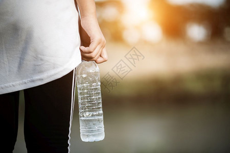 女白色的年青健身女在运动后手持水瓶自然图片