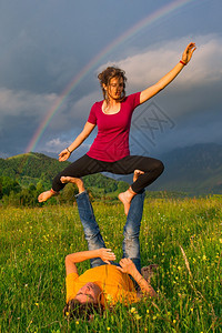 安详摆姿势Acroyoga女孩在山上的位置是男本背景是彩虹杂技瑜伽图片