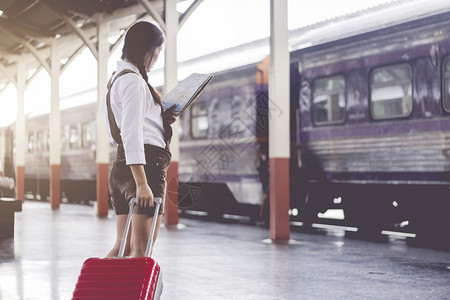 亚洲孕妇旅行在火车站旅行时用红色手提箱看假日旅行概念携带游客商业图片