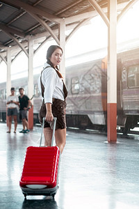 手推车商业在火站旅行中亚洲怀孕妇女旅行时携带她的牵推车红色包和周日旅行概念手提箱图片