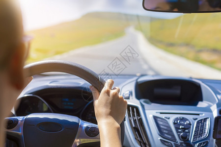 现代的人类街道在背景挡风玻璃和道路的背景下女孩在开车时手握着汽的方向盘关注她手上的焦点图片