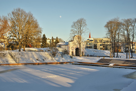 望着爱沙尼亚帕努的塔林大门在阳光明媚的冬季日子里一个由树木包围的摇摆板环绕着树丛的露台月亮罩在清蓝的天空中派尔努建筑学清除图片
