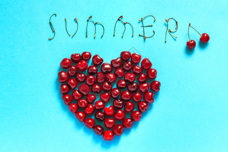 红莓樱桃的形状心脏和文字SUMEMER蓝色背景的静生平面顶视概念喜欢樱桃和生动的夏天平坦蓝色躺着图片