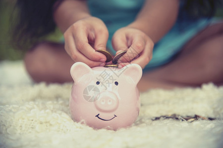 可爱的孩子在小猪银行存着硬币快乐的小投资为幸福的未来储蓄钱快乐的孩子们笑得开心的姑娘女经济家图片