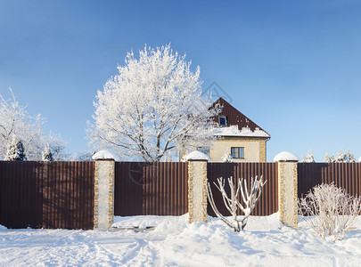 居住地雪下的美丽乡村风景在寒冷的冬天日上铁栅栏后面的石头小屋光露的树木图片