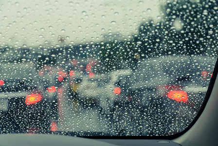 模糊在雨天的湿风屏上看到蓝色驾驶车经过湿挡风玻璃出去过滤图片