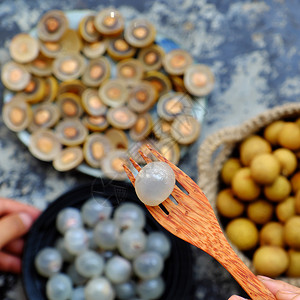 种子亚洲击越南最顶端的热带甜水浆果用黑盘上含种黄皮切成一半龙眼水果背景的长南肉在黑盘上以半透明白封图片