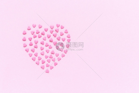 粉红色糖果的心洒在形上位于柔和的粉红色背景中心概念Valentinersquos卡顶视图复制文本空间象征甜点五彩纸屑图片