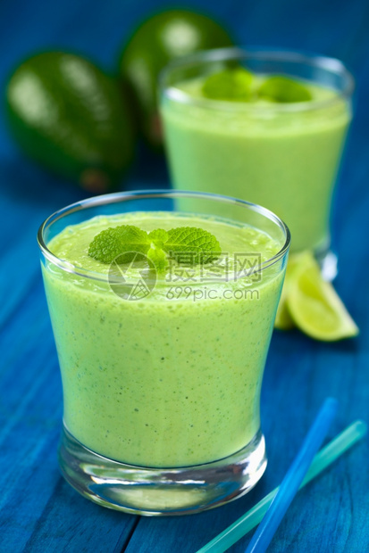 制作由新鲜的avocado石灰和酸奶制成的健康清新绿色冰沙配有薄荷糖在蓝木选择焦点上戴眼镜聚焦于饮料上的大薄荷叶食物泥图片
