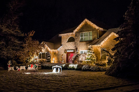 大量的晚上为圣诞节装饰的房子晚上为圣诞节装饰的房子被雪覆盖童话正面图片