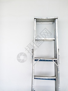 铝的折叠梯子躺在白水泥墙上行业爬工作图片
