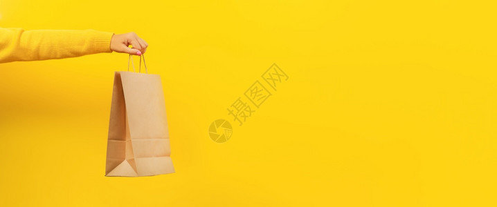 黄色的包妇女手持黄色背景折扣纸袋和销售全景形象概念的纸袋以购买黄本底折扣和出售商业图片
