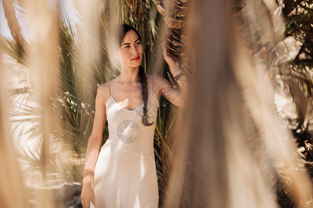 年轻的木制身着白衣服靠近沙漠棕榈树边的年轻女子白种人图片