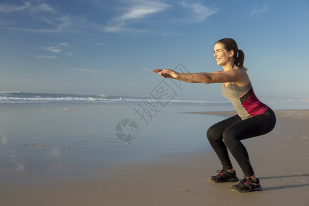 女士闲暇年轻的拍到一个美丽女人在海滩上做蹲下运动图片