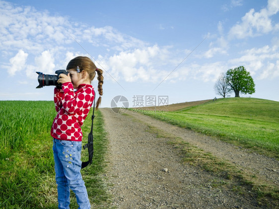 爱好水平的草年轻女孩在瑞士农村有一台大相机在拍摄风景时下照片图片