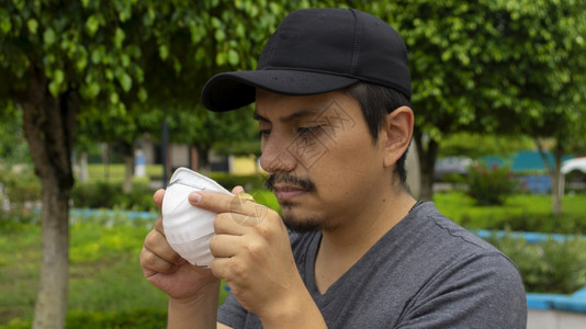 拉戈街道保护上拉丁男子盯着他双手拿的白色面罩准备戴上的近景图片