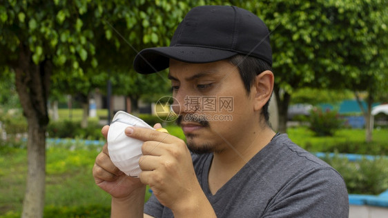 拉戈街道保护上拉丁男子盯着他双手拿的白色面罩准备戴上的近景图片