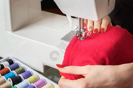 材料缝纫机上的女青年缝纫织物在涂上彩色池子阶段的缝合过程丰富多彩的手图片