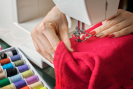 缝纫机上的女青年缝纫织物在涂上彩色池子阶段的缝合过程有色工厂作图片