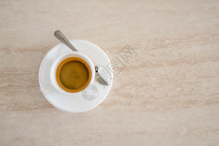 新鲜的液体棕色带有金属勺子背面和复制空间的白色咖啡杯顶端视图图片