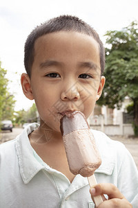 快乐的奶油近距离面对亚洲男孩吃巧克力冰淇淋和快乐面孔童年图片