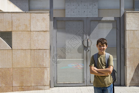 吸引人的青年携带着他的背包好孩子站在学校门口着图片