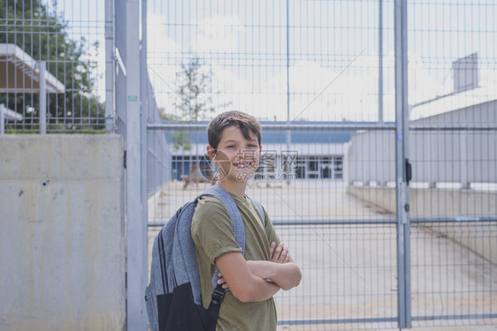 吸引人的常设带着他背包好孩子站在学校门口着男图片