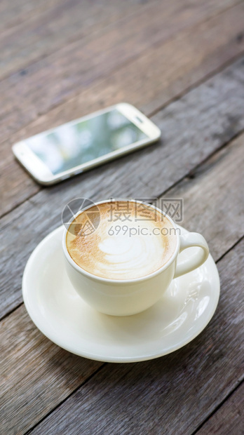 刷新木制桌上的热咖啡和智能手机早餐棕色的图片