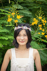 草地公园美丽的亚洲年轻女子带着一朵花的皇冠夏天图片