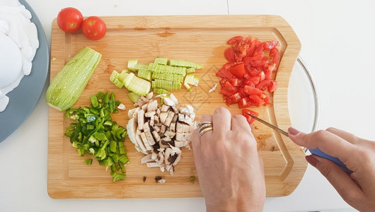 素食主义者帕利卡拉斯石板在木切上用砍手和切蔬菜割板上的顶部视图图片