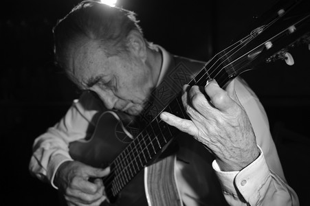爵士乐一个穿白衬衫的老人弹着声音吉他黑暗背景单色焦点在手音乐细绳图片