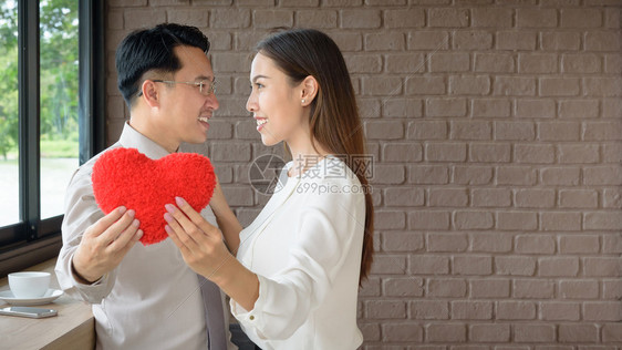 特别的夫妻情爱男人和女怀着红色的心爱和情人节的概念给予女士图片