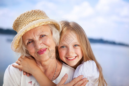 孩子蓝色的欢乐祖母和外孙女肖像看着阳光夏日的摄影机金发女郎图片
