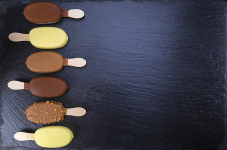 食物美味的黑石板上覆盖着巧克力的棒冰淇淋专注于棒上覆盖着黑色巧克力的冰淇淋坚果图片