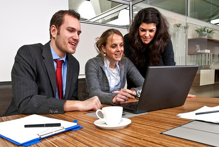 桌子初级移动的三名工作人员在浏览笔记本电脑时讨论财务事项同时浏览笔记本电脑图片
