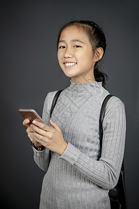 女孩手表拿着智能机的亚洲青少年笑面脸有如肖像般的牙齿微笑游戏图片