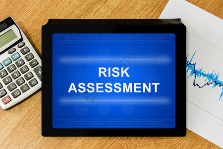 安全控制挑战带有计算器和财务图表的数码平板电脑上风险评估单词图片